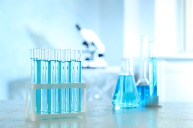 Photo of Test tubes with light blue liquid on table in laboratory. Space for text