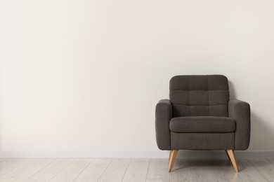 Photo of Comfortable armchair near white wall in room, space for text