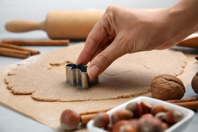 Photo of Woman making gingerbread man with cutter at table, closeup. Homemade Christmas biscuits