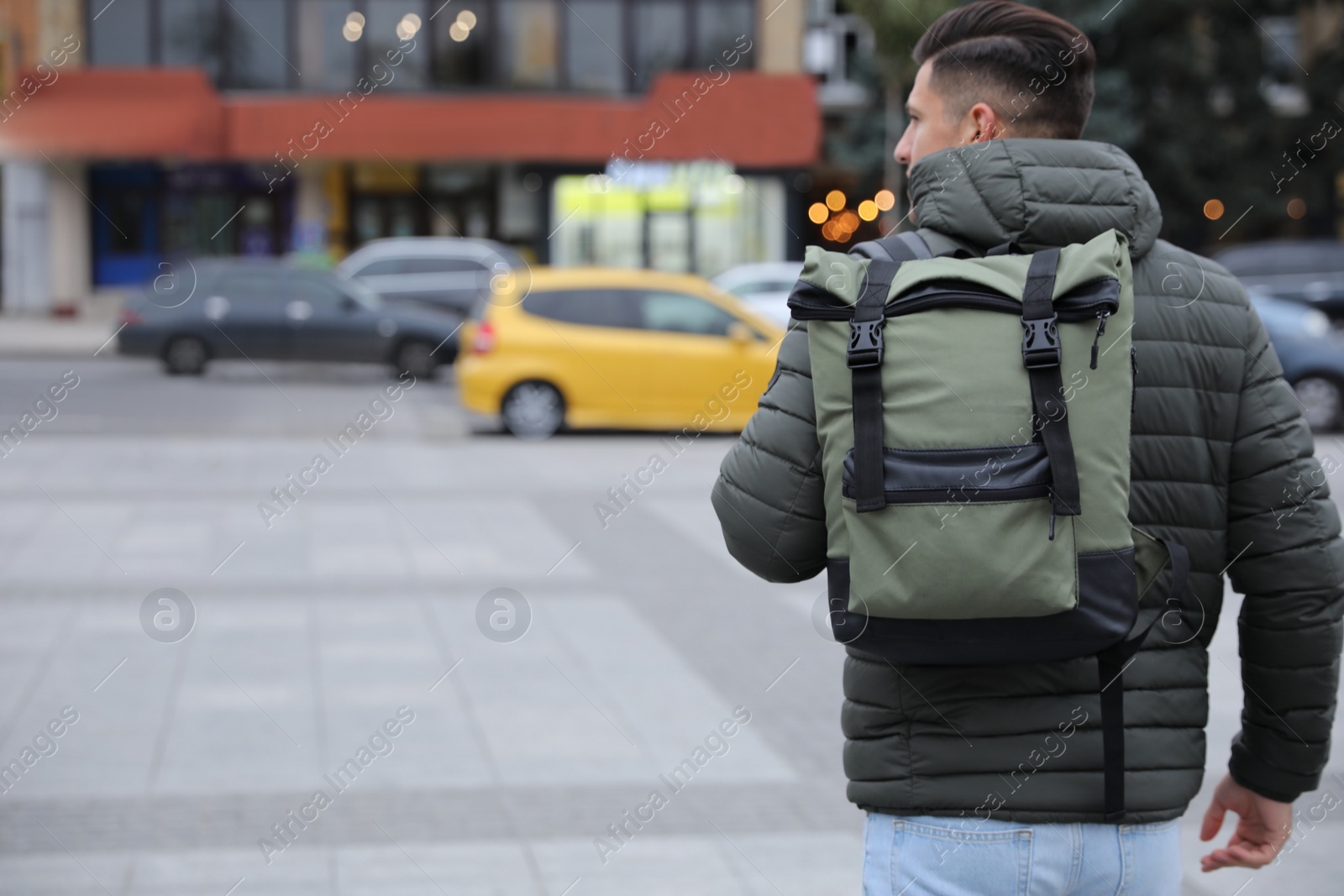 Photo of Male tourist with travel backpack on city street, back view. Urban trip