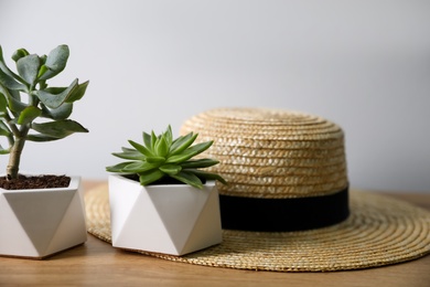 Beautiful succulents and hat on wooden table. Interior decoration, closeup