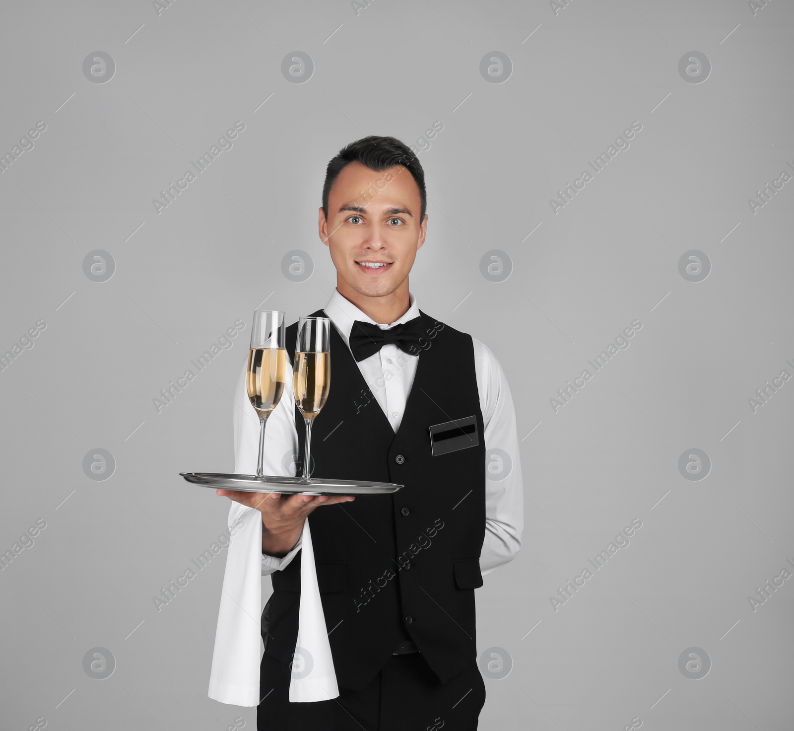 Photo of Waiter holding metal tray with glasses of champagne on grey background