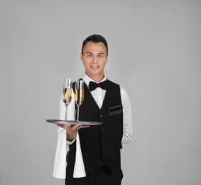 Photo of Waiter holding metal tray with glasses of champagne on grey background