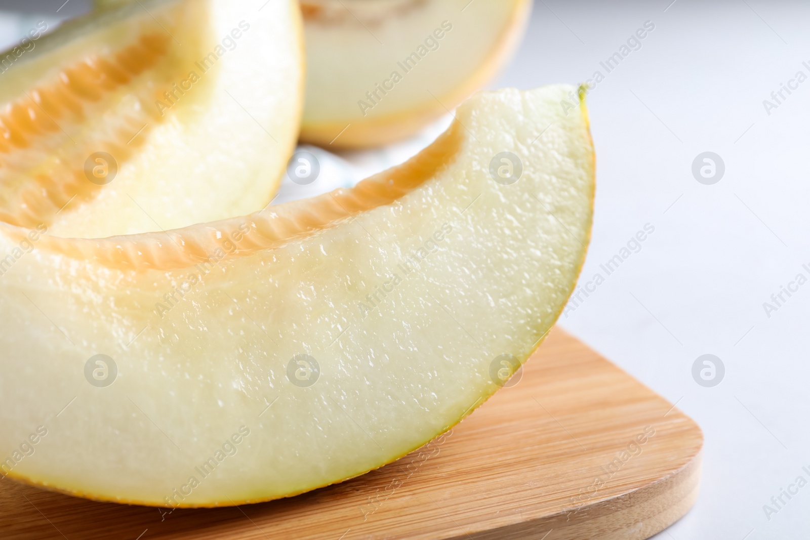 Photo of Pieces of delicious honeydew melon on wooden board, closeup