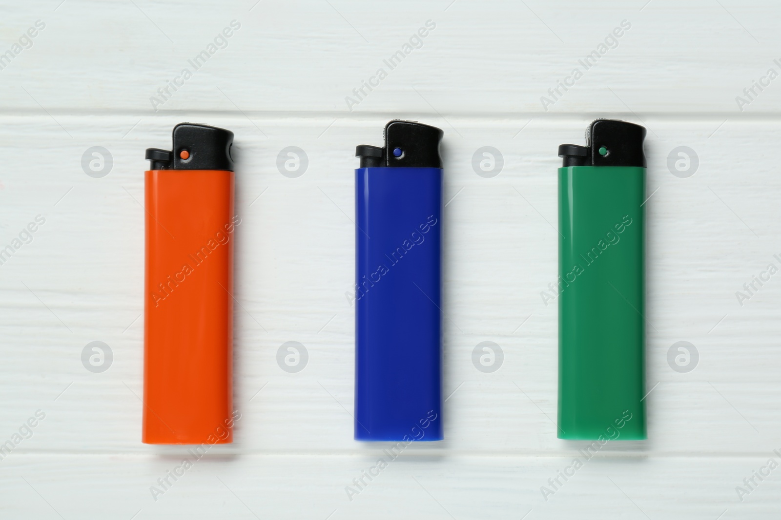 Photo of Stylish small pocket lighters on white wooden background, flat lay