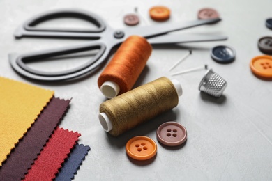 Set of tailoring accessories and fabric on light background