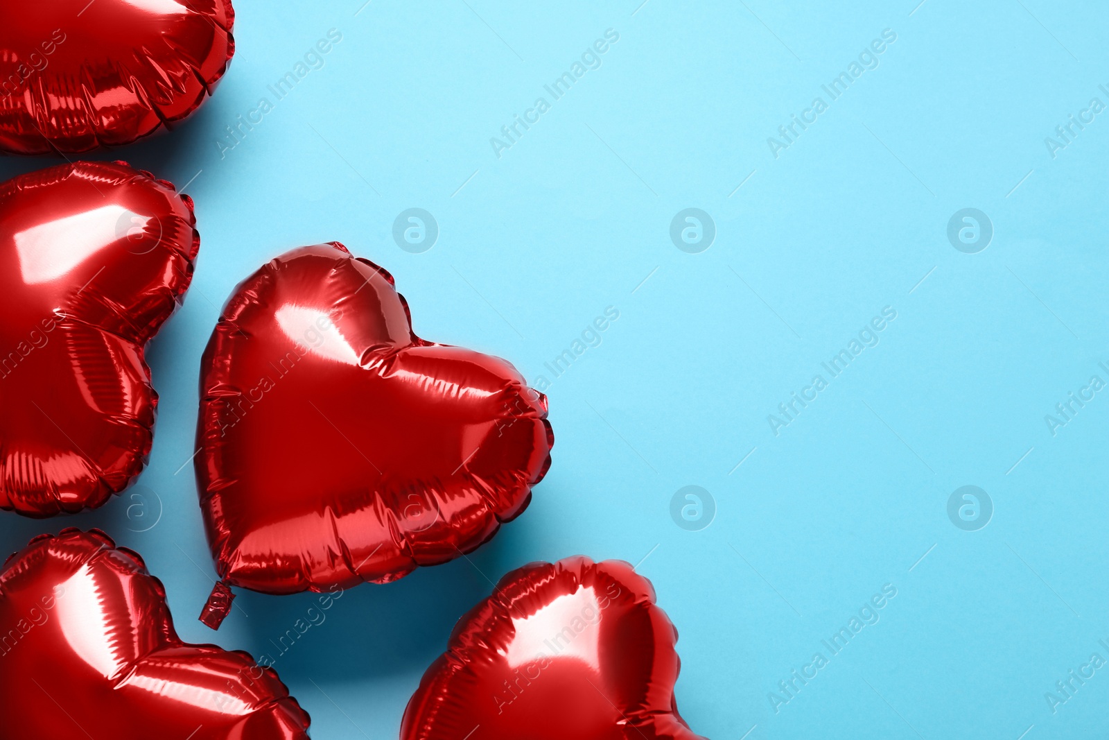 Photo of Red heart shaped balloons on light blue background, flat lay with space for text. Valentine's Day celebration