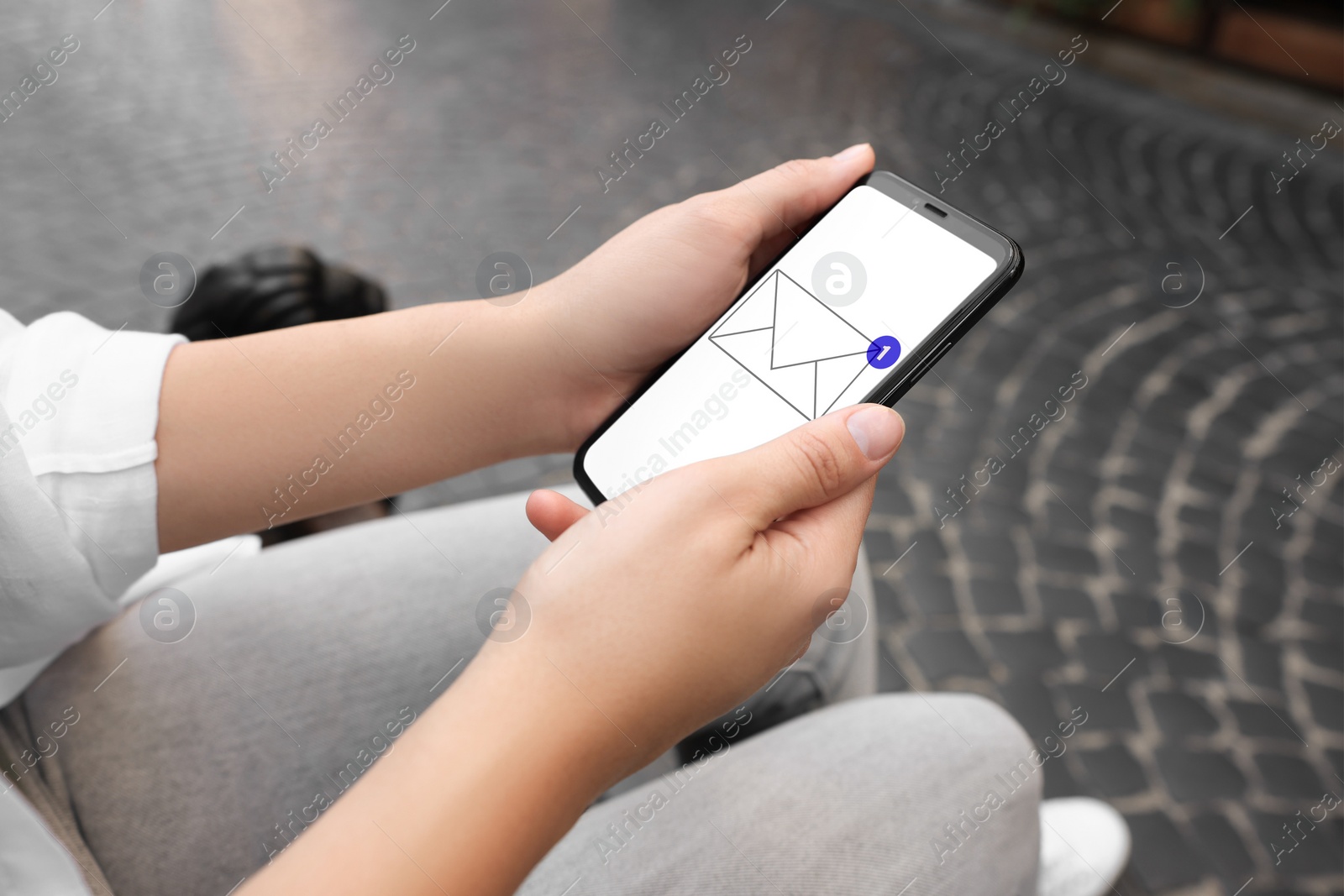 Image of Woman received message on mobile phone outdoors, closeup. Envelope illustration on device screen