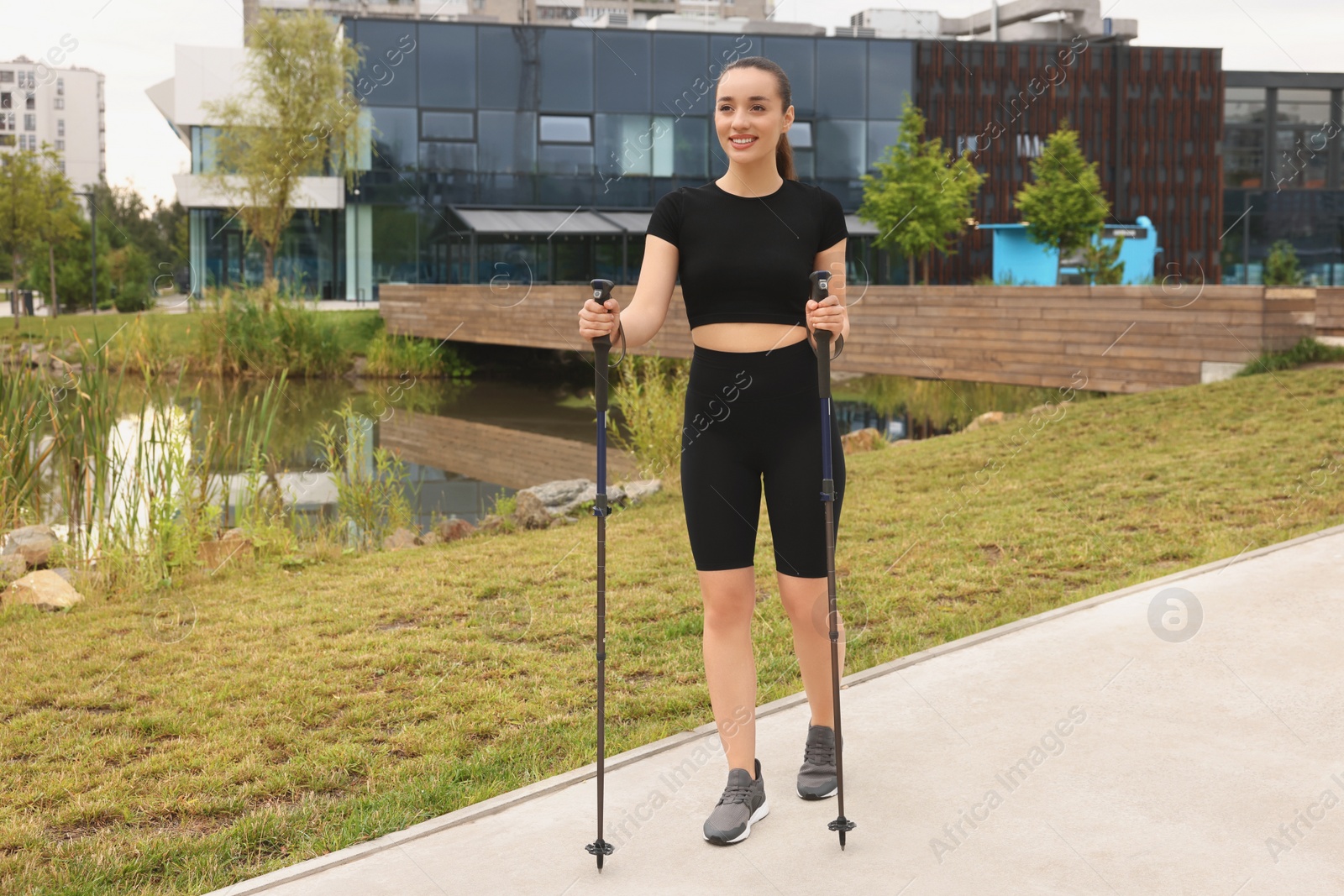 Photo of Young woman practicing Nordic walking with poles outdoors