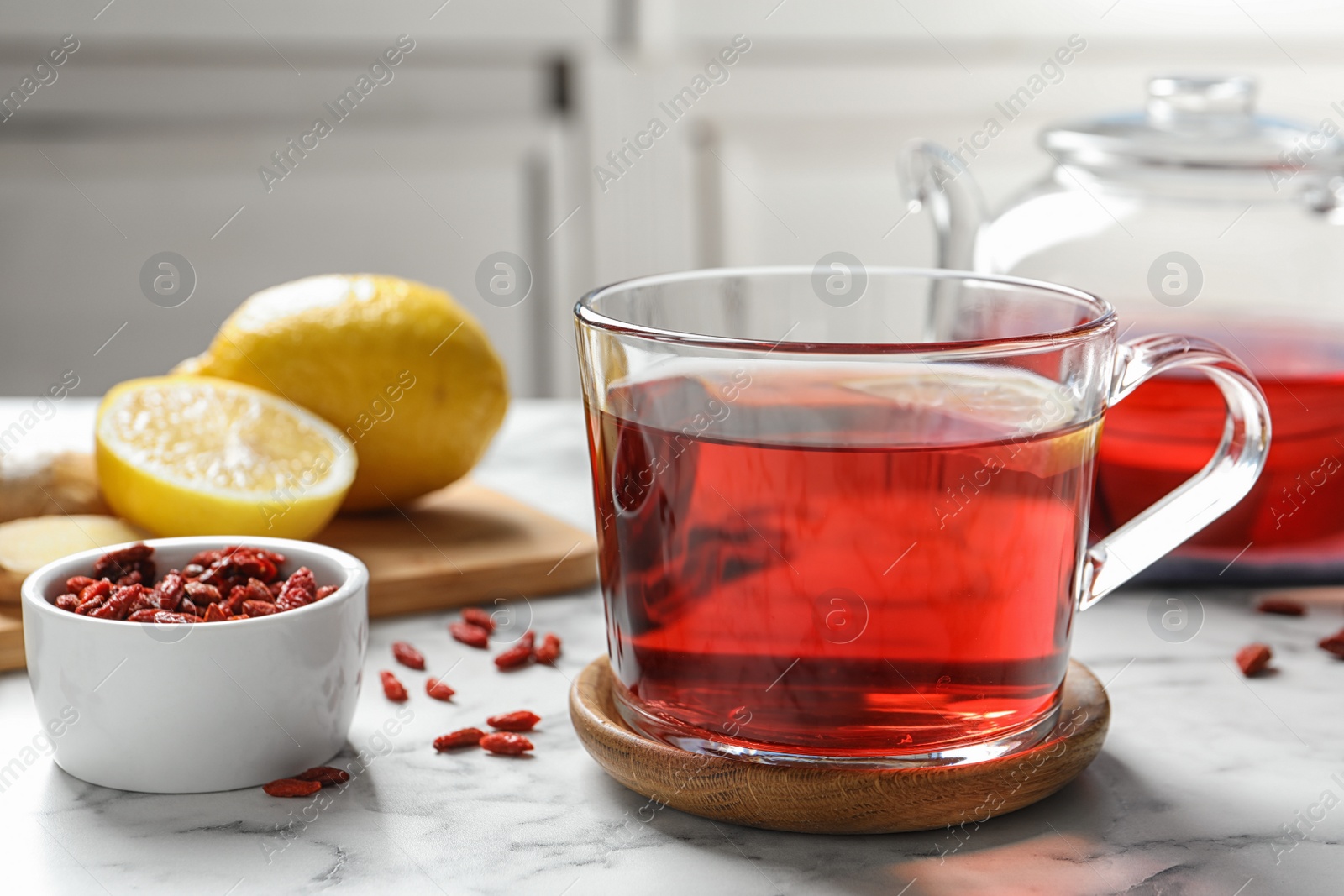 Photo of Healthy goji tea with lemon in glass cup on marble table