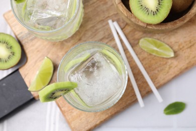 Photo of Refreshing drink, cut kiwi and lime on white table, flat lay