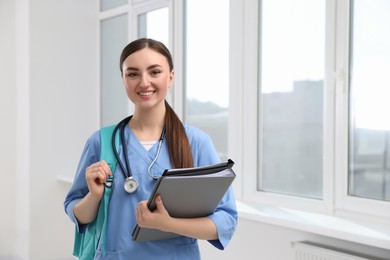 Photo of Smart medical student with folders in college hallway, space for text