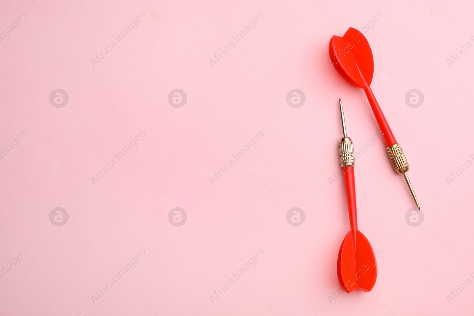 Photo of Red dart arrows on pink background, flat lay with space for text