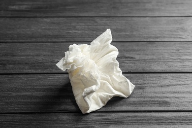 Photo of Crumpled paper napkin on wooden background. Personal hygiene