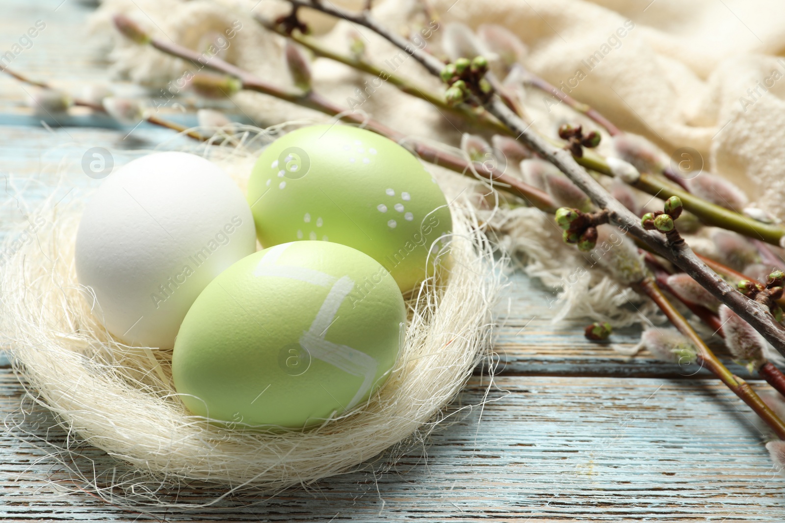 Photo of Sisal nest with painted Easter eggs on wooden table, space for text