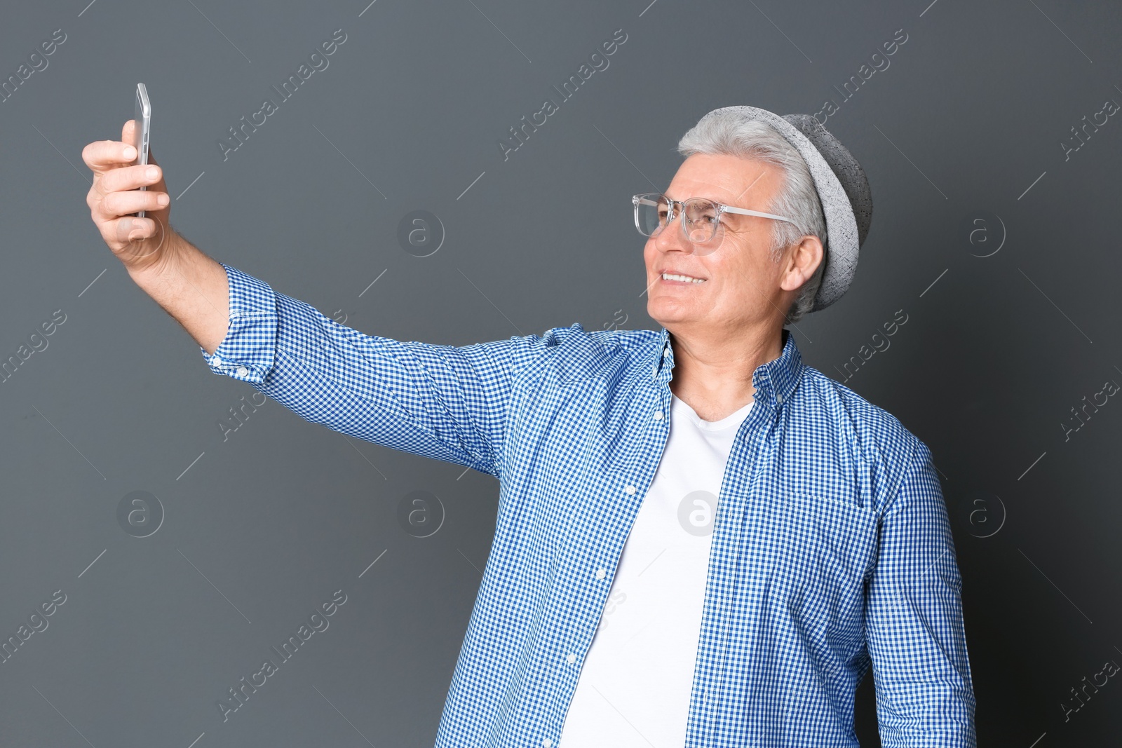 Photo of Mature man taking selfie against grey background