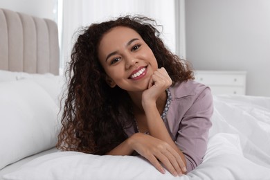 Photo of Happy African American woman lying on bed at home