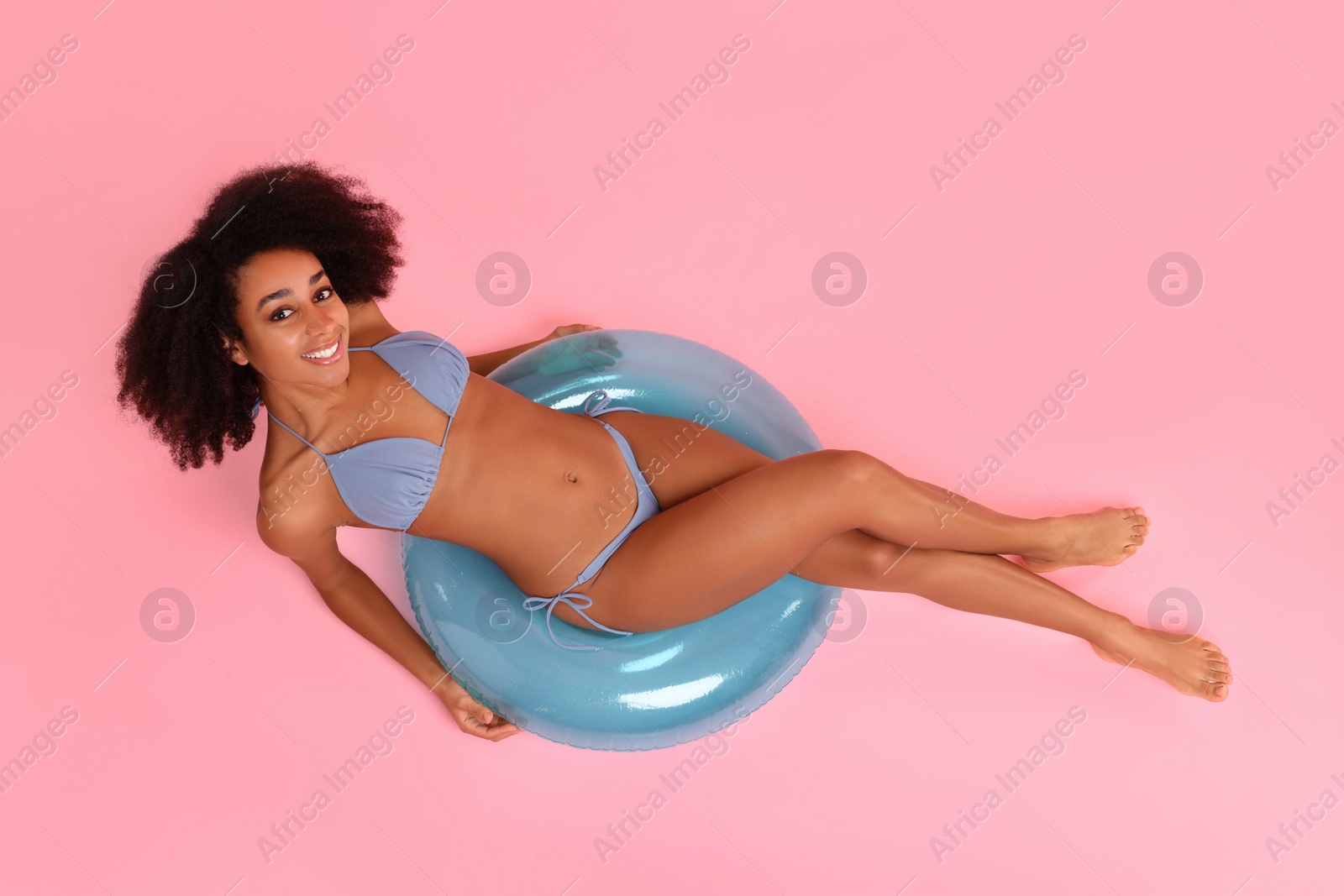 Photo of Beautiful woman in stylish bikini with inflatable ring on pink background, top view