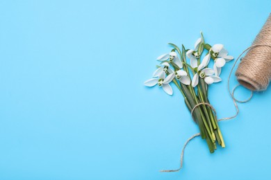 Photo of Beautiful snowdrops and twine on light blue background, flat lay. Space for text