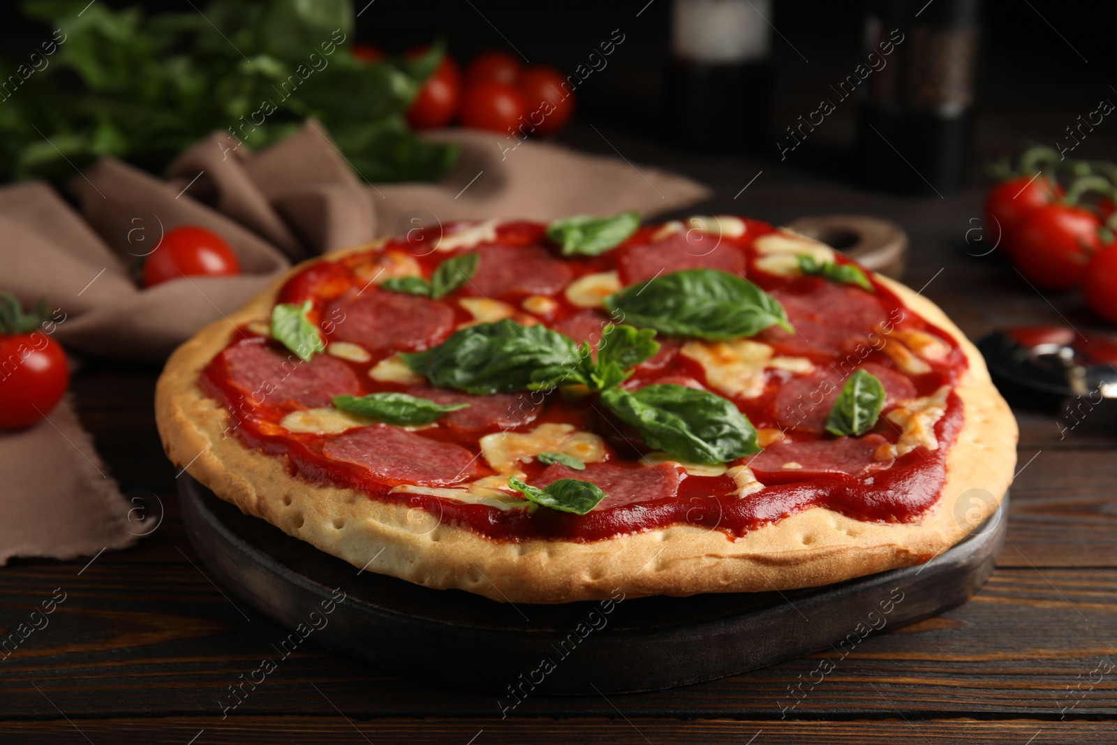 Photo of Pita pizza with pepperoni, cheese and basil on wooden table, closeup