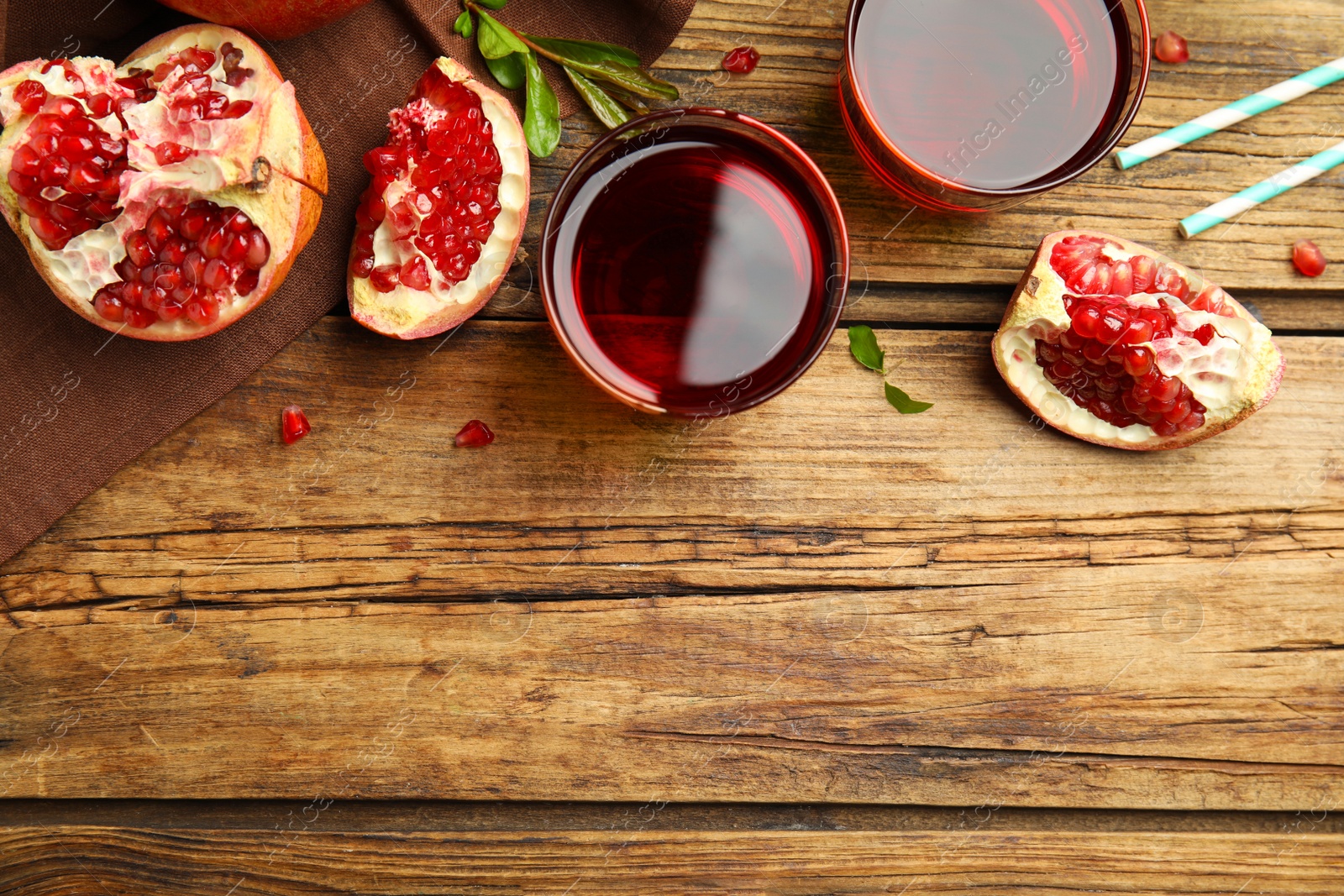 Photo of Freshly made pomegranate juice on wooden table, flat lay. Space for text