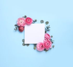 Photo of Beautiful ranunculus flowers and paper card on light blue background, flat lay. Space for text