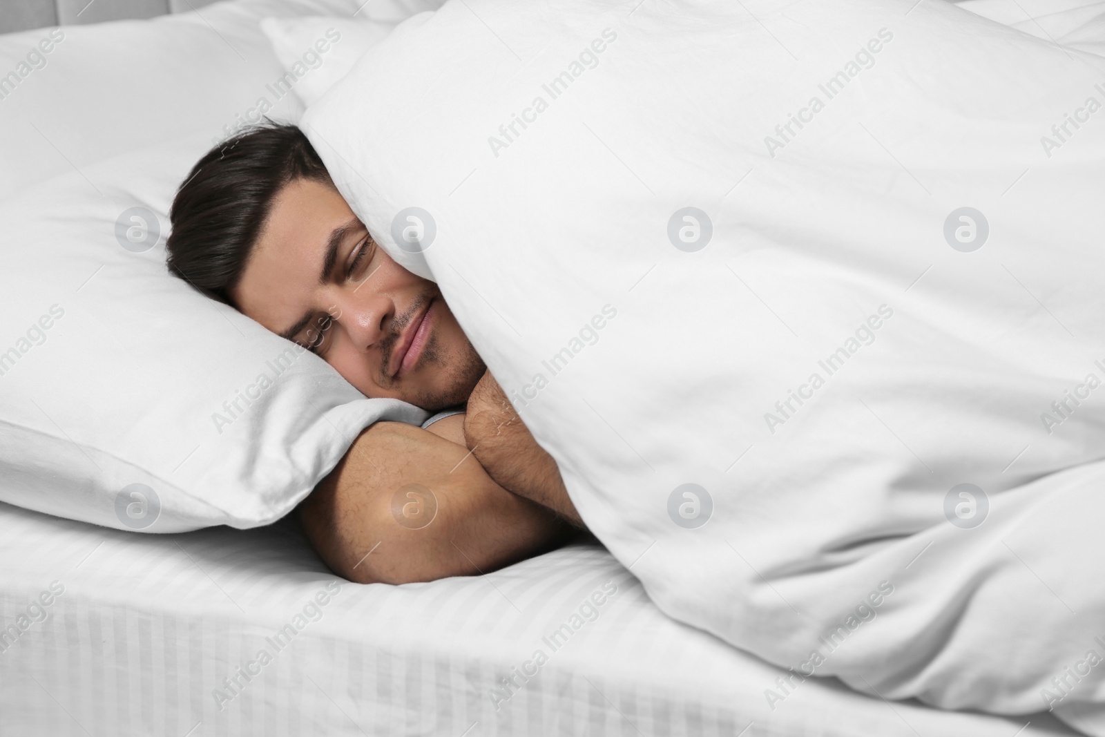 Photo of Handsome man sleeping under soft blanket in bed at home
