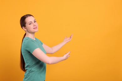 Photo of Happy woman inviting to come in against orange background, space for text