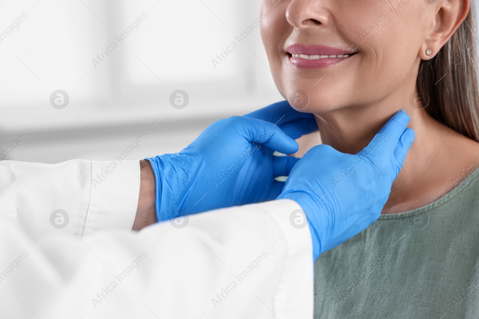 Photo of Endocrinologist examining thyroid gland of patient indoors, closeup