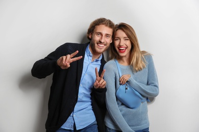 Young woman in warm sweater and man wearing knitted cardigan on white background