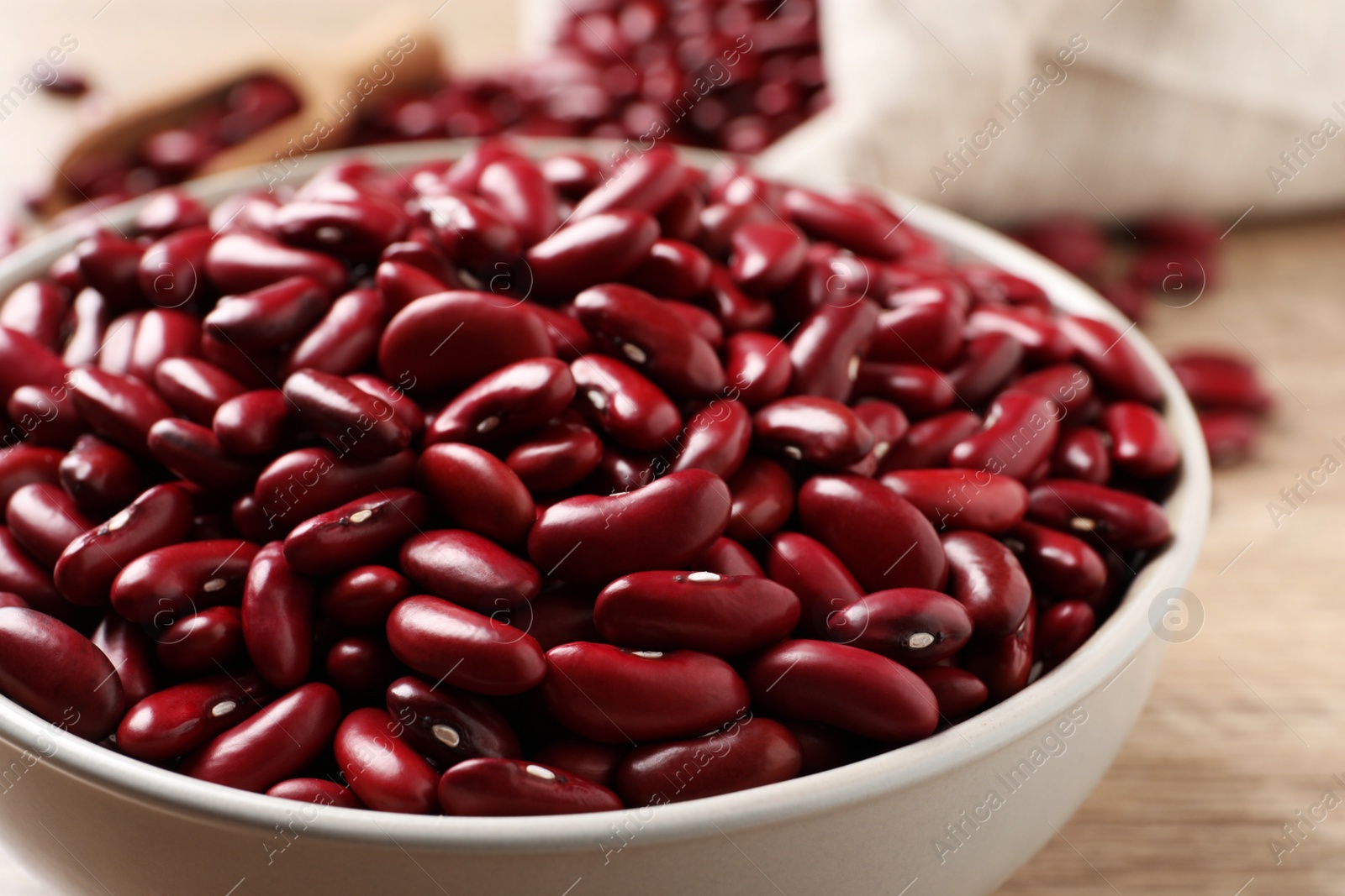 Photo of Raw red kidney beans in bowl on table, closeup