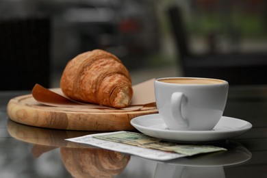 Photo of Croissant, coffee, tips and receipt on table