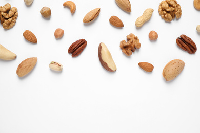 Photo of Different delicious nuts on white background, flat lay. Space for text