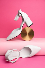 Photo of Stylish white female shoes and decor on pink background