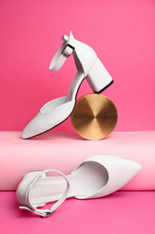 Stylish white female shoes and decor on pink background