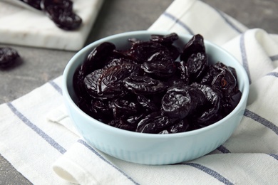 Photo of Bowl of sweet dried plums on table. Healthy fruit