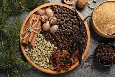 Photo of Different spices, nuts and fir branches on gray textured table, flat lay