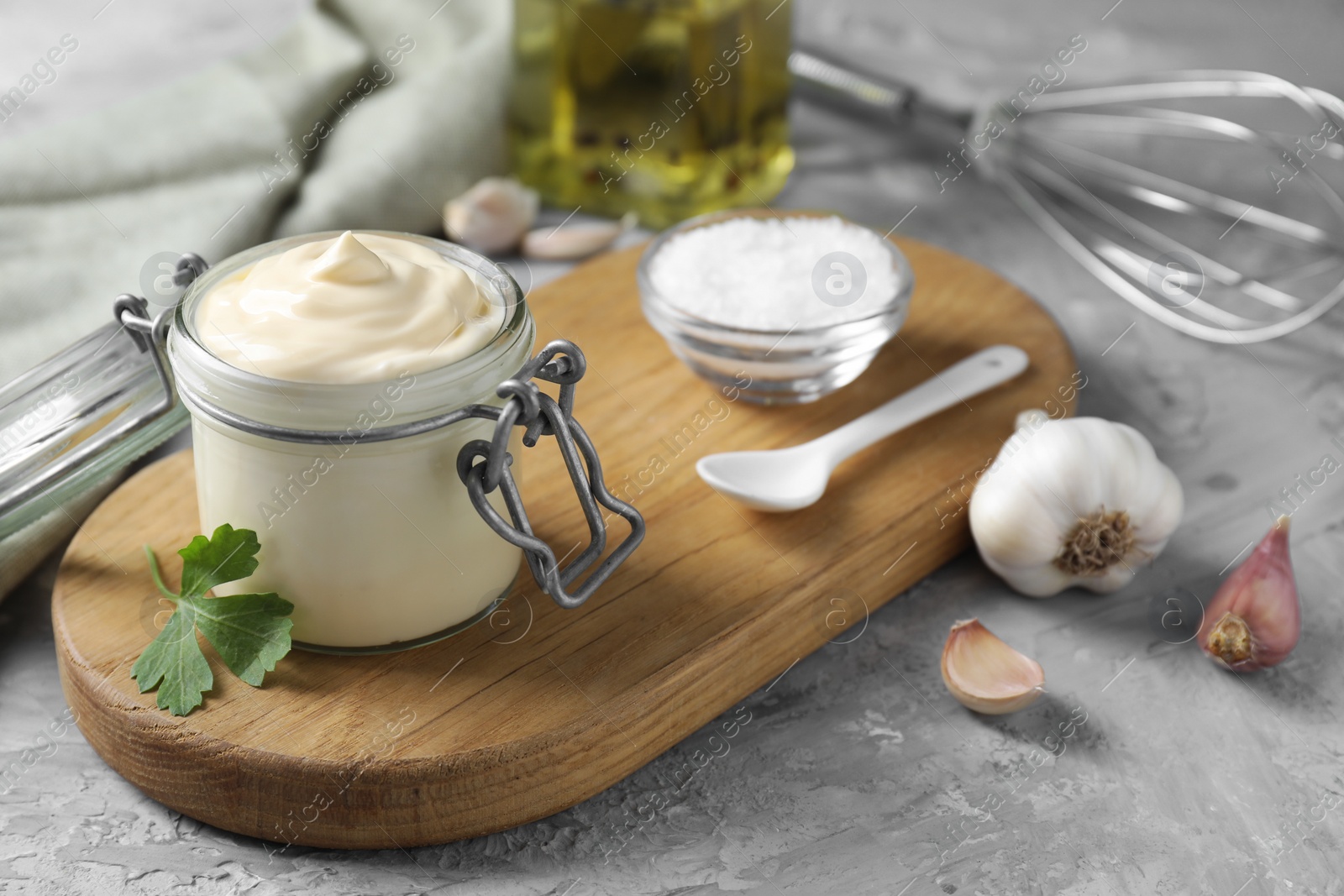 Photo of Tasty mayonnaise in jar and ingredients on gray table, closeup