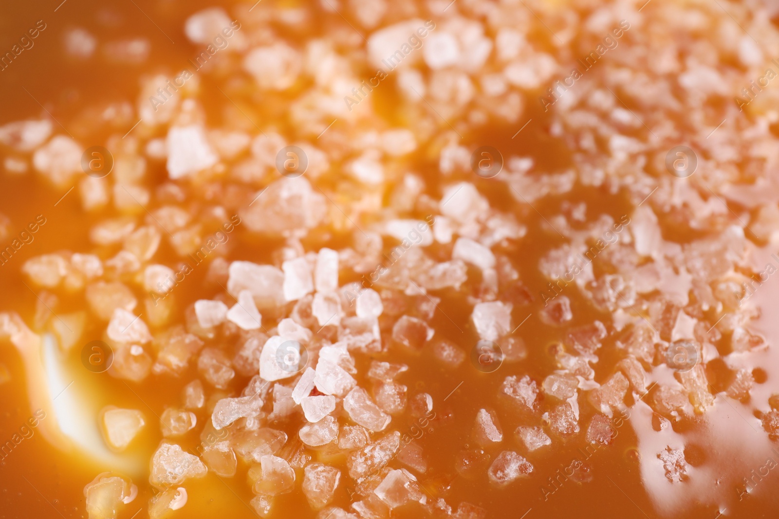 Photo of Delicious caramel sauce with sea salt as background, closeup