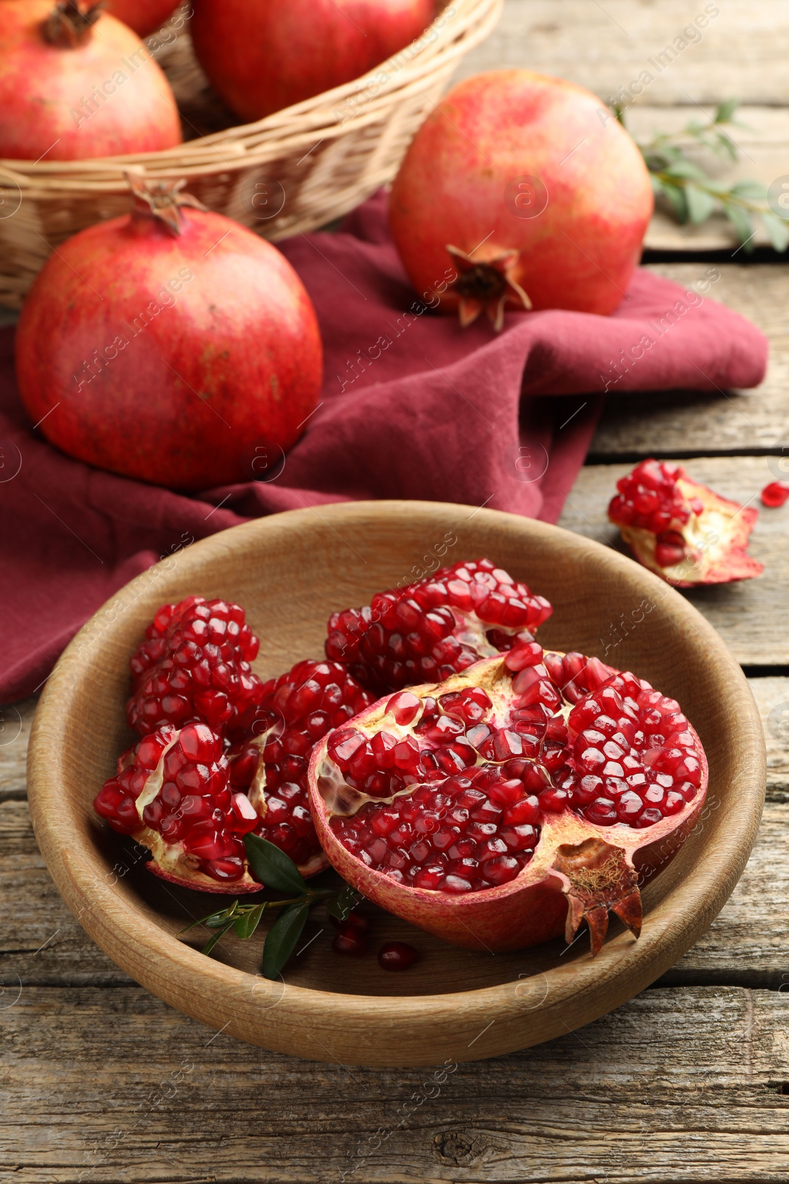 Photo of Fresh pomegranates and green leaves on wooden table