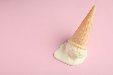 Photo of Melted vanilla ice cream in wafer cone on pink background, above view. Space for text