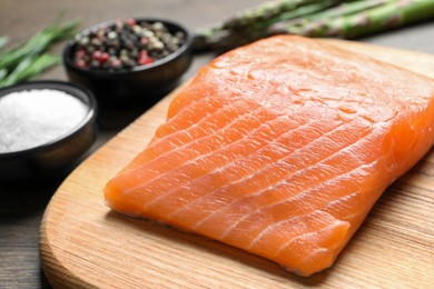 Photo of Fresh raw salmon and ingredients for marinade on wooden table, closeup