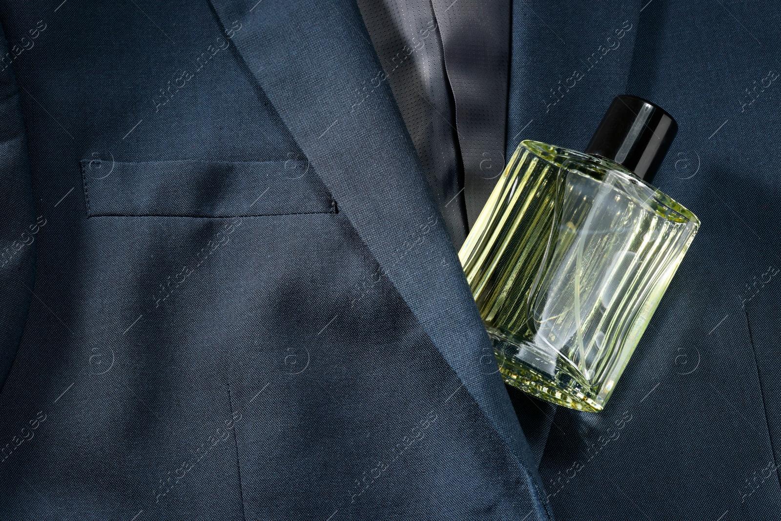 Photo of Luxury men's perfume in bottle on grey jacket, top view. Space for text