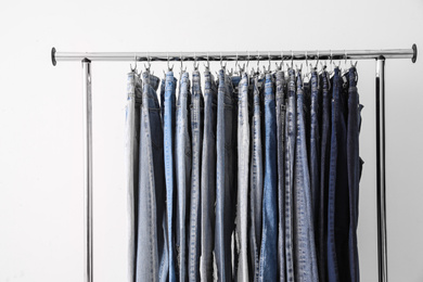 Photo of Rack with different jeans on light background