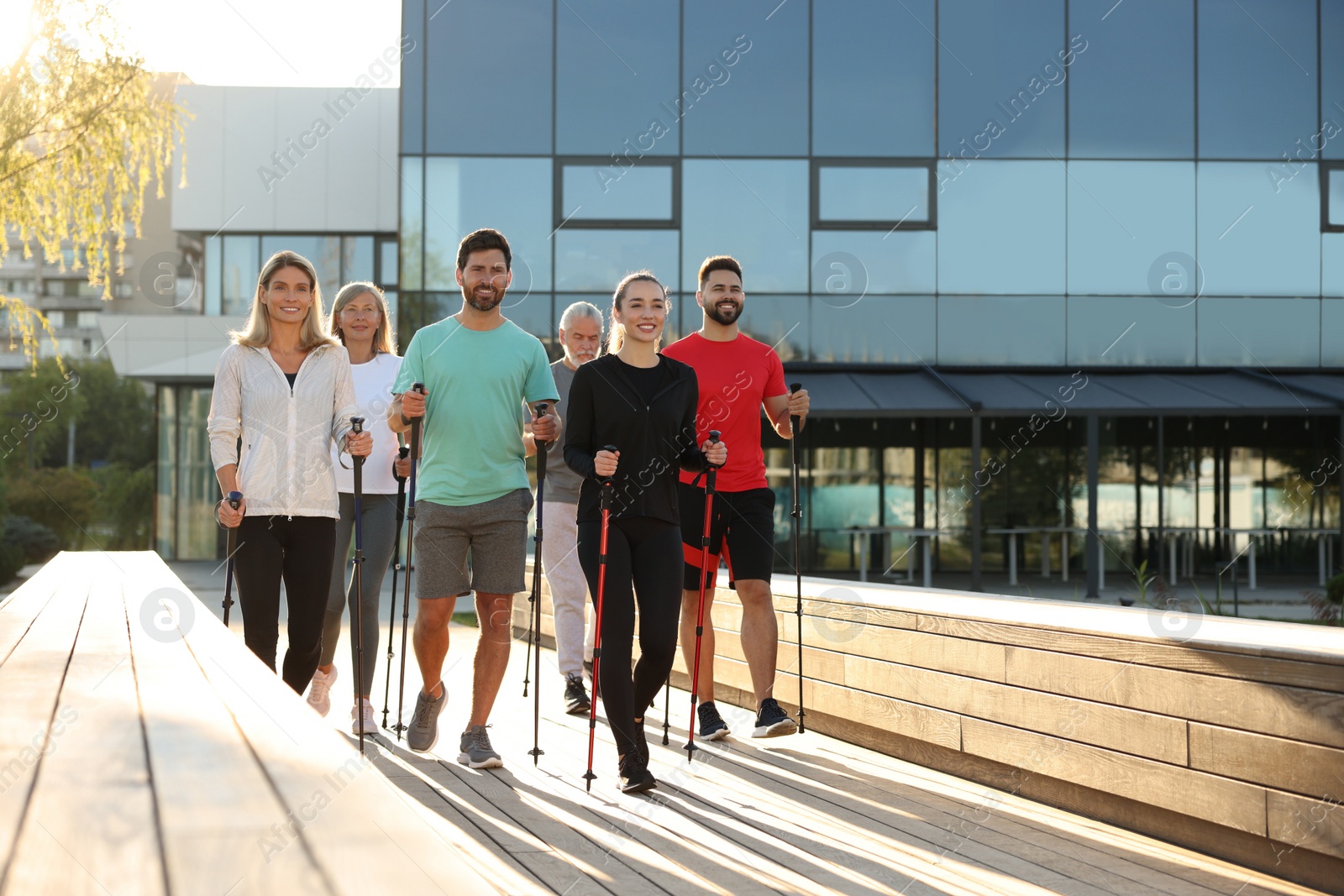 Photo of Group of people practicing Nordic walking with poles outdoors on sunny day