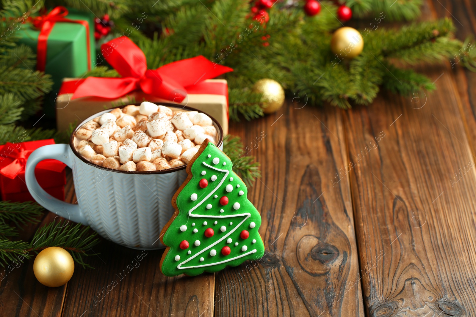 Photo of Tasty Christmas cookie in shape of fir tree, cocoa with marshmallows and festive decor on wooden table, closeup. Space for text