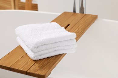 Photo of Stacked soft towels on tub tray in bathroom