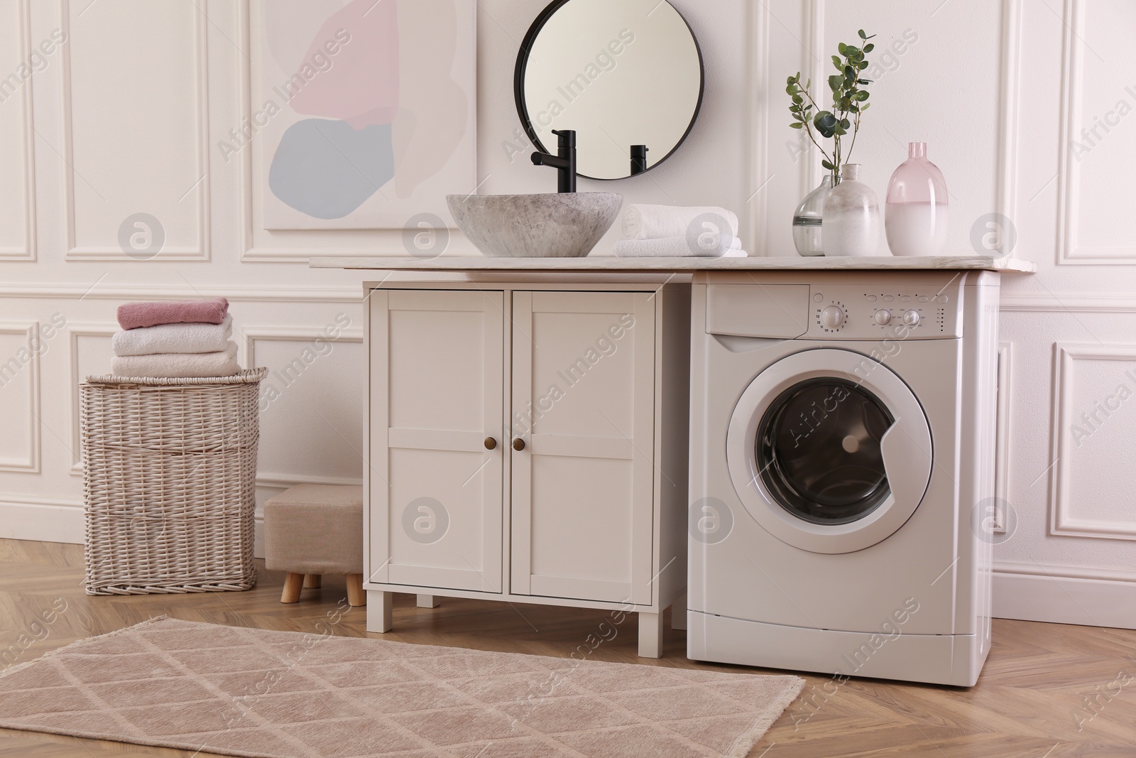 Photo of Laundry room interior with modern washing machine and stylish vessel sink on countertop