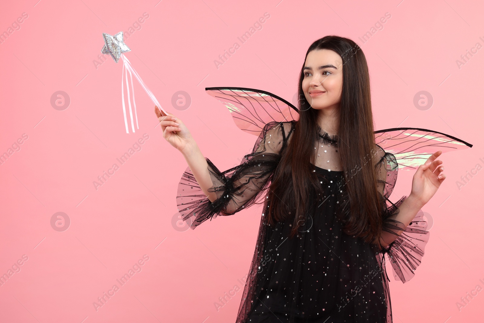 Photo of Beautiful girl in fairy costume with wings and magic wand on pink background