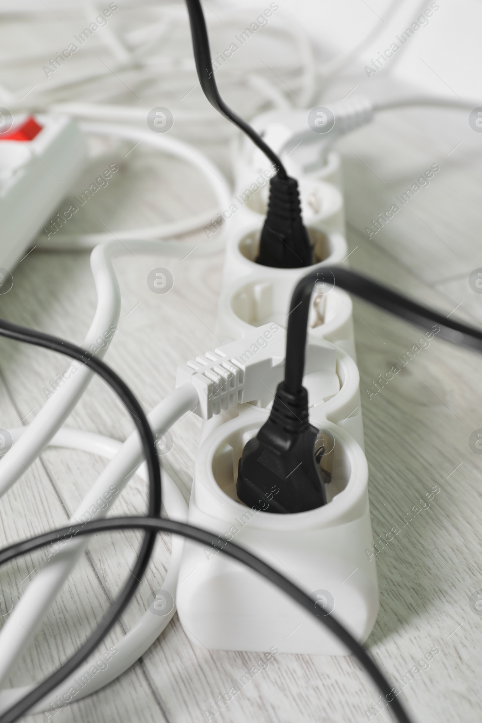 Photo of Power strip with different electrical plugs on white floor, closeup